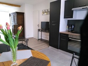 Una cocina moderna con gabinetes negros, estufa a gas y una cafetera. Hay una mesa de comedor con un florero.