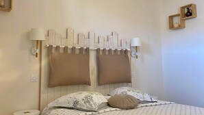 Ett sovrum med en säng, ett sängbord, en lampa och en hängande taklampa.
