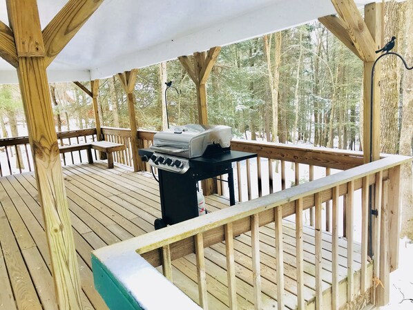 Eine Holzterrasse mit Grill und Bank.