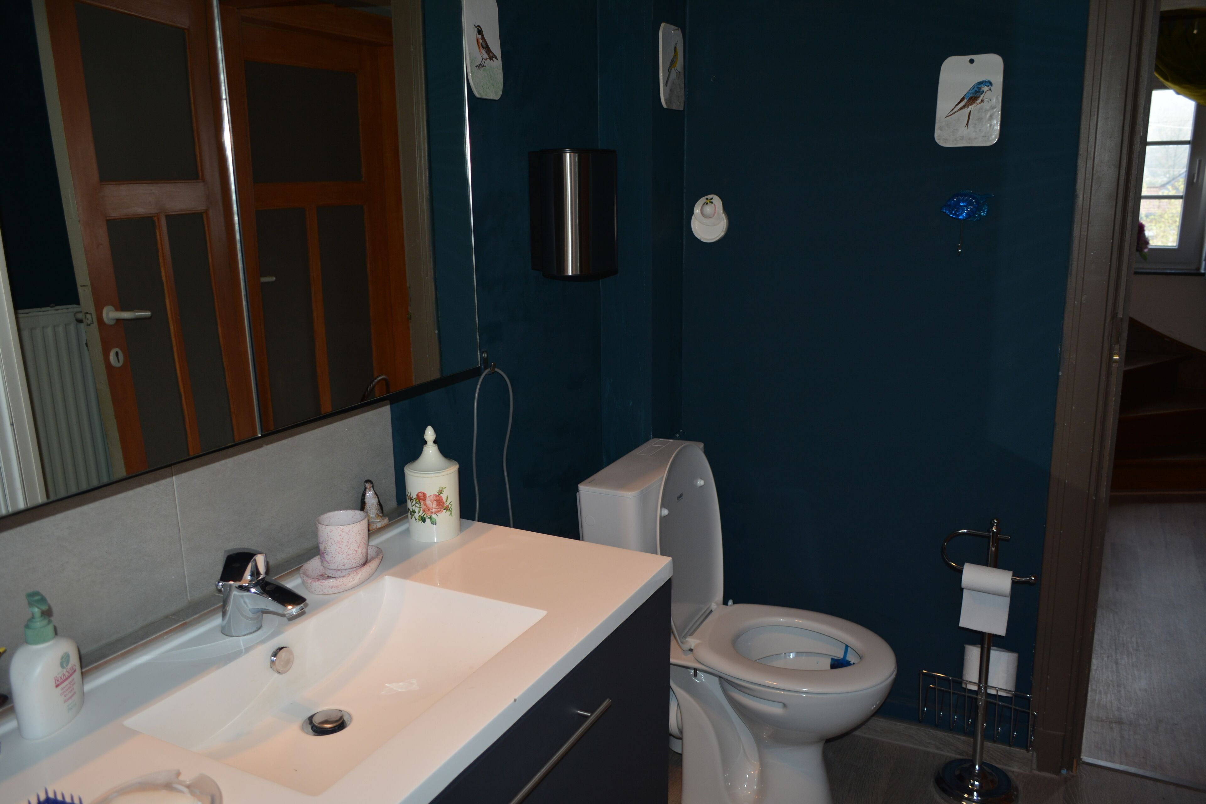 A bathroom with a white sink, a toilet, and a mirror.