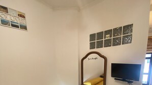 Une chambre d’hôtel avec un lit, une télévision, une table de chevet et un mur orné de tableaux.