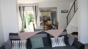 Un salon avec un canapé, une table à manger et une cuisine en arrière-plan.