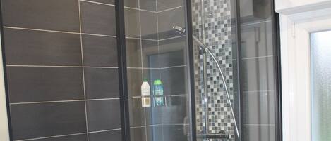 Une cabine de douche moderne dotée d’une porte en verre et d’un sol carrelé.