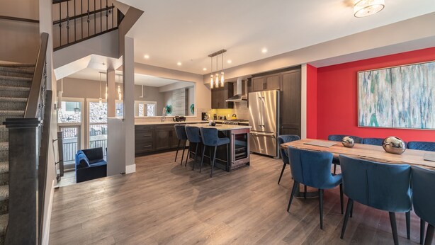 Een moderne keuken met een centraal eiland, barstoelen en een eettafel met stoelen.