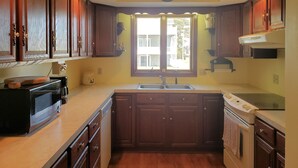 Una cocina con armarios de madera, un microondas, un fregadero y un horno.