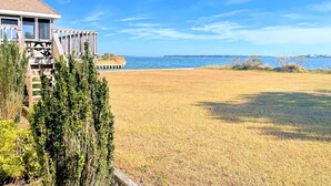 Una propiedad costera con terraza de madera que da a un campo verde y al mar.