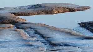 Un paysage naturel avec une étendue d’eau qui reflète les arbres et un terrain rocheux.