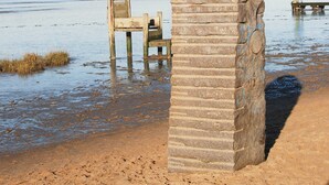 Une plage avec une structure en pierre et une chaise en bois.