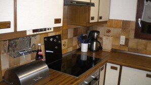 Una cocina con armarios de madera, un tostador de acero inoxidable, una cafetera y un lavamanos.