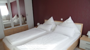 Una cama doble con ropa de cama blanca, un cabecero de madera y una mesita de noche con lámpara.
