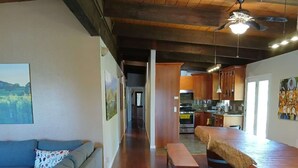 A spacious living area with a wooden floor, a sofa, a dining table, and a kitchen in the background. - Green Valley, Sonoma County Vacation Rental at a Working Winery. (Sebastopol)