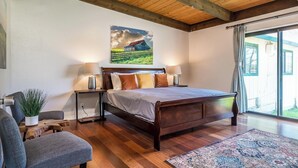 A bedroom with a wooden bed, two bedside tables with lamps, a large window, and a view of the outdoors. - Green Valley, Sonoma County Vacation Rental at a Working Winery. (Sebastopol)