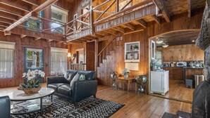 Un interior espacioso de madera con sala de estar, una escalera y una cocina.