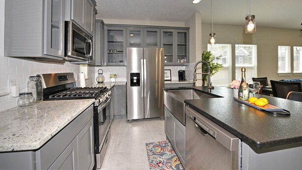 A modern kitchen with stainless steel appliances, a granite countertop, and a dining area with a view of the outside. - RIVERWALK/ALAMODOME TOWNHOME - WITH HOT TUB & Wood Fire Pit!1 MILE TO RIVERWALK  (San Antonio)