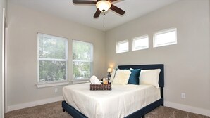 A bedroom with a bed, a ceiling fan, and three windows. - RIVERWALK/ALAMODOME TOWNHOME - WITH HOT TUB & Wood Fire Pit!1 MILE TO RIVERWALK  (San Antonio)
