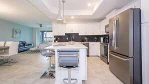 A modern kitchen with white cabinets, stainless steel appliances, and a central island with bar stools.