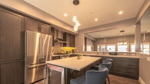 Una cocina moderna con una isla central, electrodomésticos de acero inoxidable y un amplio ventanal con vistas a la ciudad.