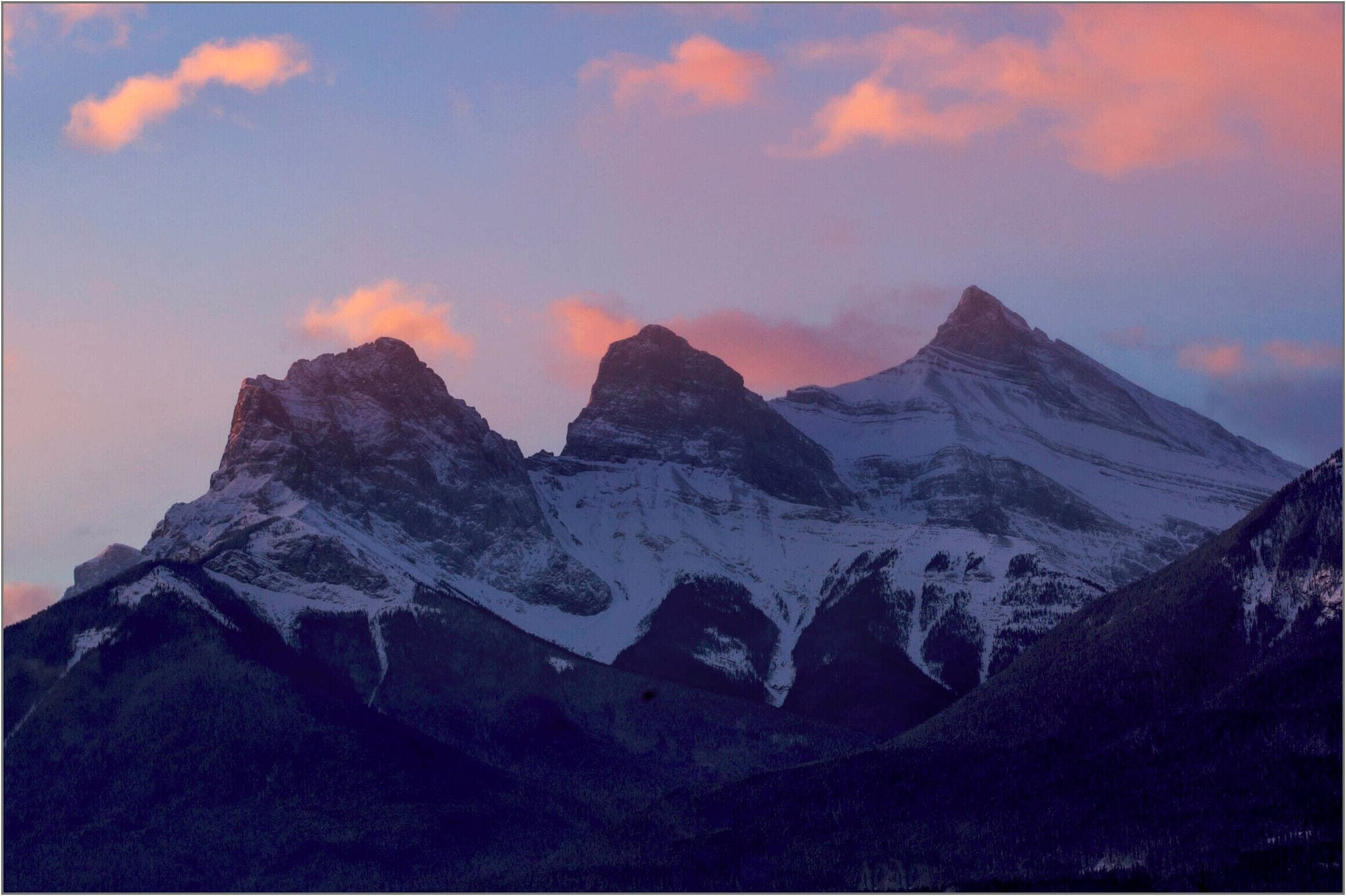 A mountain range with snow-covered peaks and a clear sky.