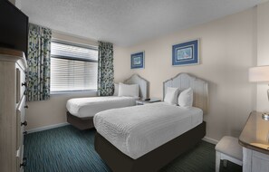 Une chambre d’hôtel avec deux lits, un bureau et une chaise.