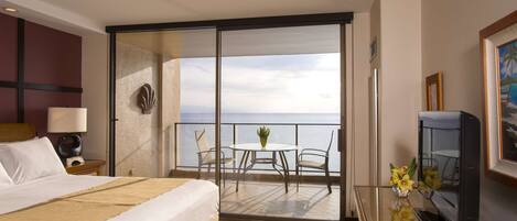 Et hotelværelse med seng, skrivebord med fjernsyn, balkon med bord og stole samt havudsigt.