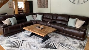 A spacious living room with a large sectional sofa, a wooden coffee table, and a patterned rug.