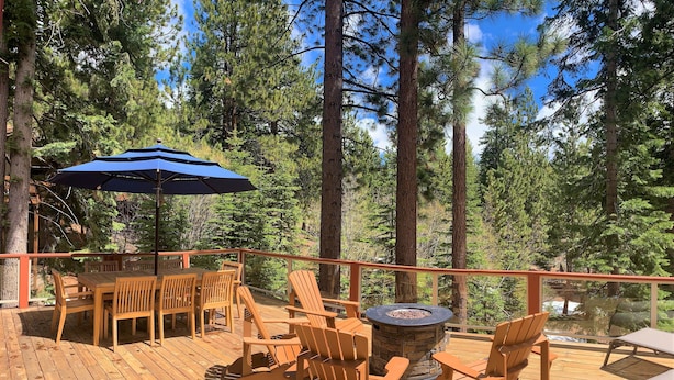 A wooden deck with outdoor furniture, including a table and chairs, and a fire pit.