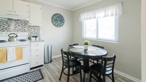 A kitchen with white cabinets, a stove, and a clock on the wall. - Cute Condo in Rock Hill-45 (Rock Hill)