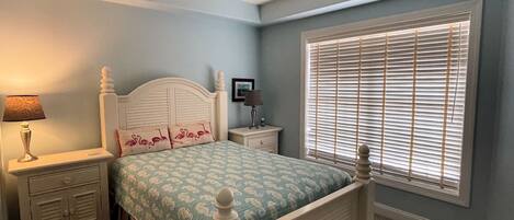 A bedroom with a bed, nightstands, a ceiling fan, and a window with blinds.