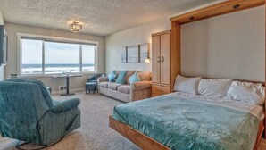 Ein Schlafzimmer mit einem großen Bett, einem Sofa, einem Schreibtisch und Blick aufs Meer.