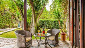 Une terrasse extérieure avec des meubles en osier et une table où sont servis des boissons.