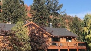 A two-story log cabin with a balcony, surrounded by dense forest. - Welcome to our Mountain Family Cabin near Lava Hot Springs!  (Bancroft)
