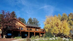 A wooden lodge with a covered porch and multiple windows, surrounded by trees and a clear sky. - Welcome to our Mountain Family Cabin near Lava Hot Springs!  (Bancroft)