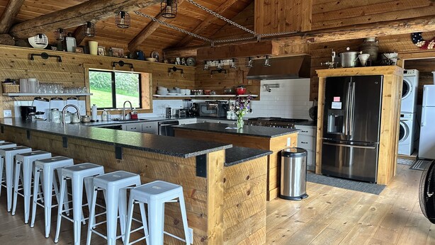 A modern kitchen with a wooden island, bar stools, stainless steel appliances, and a large window. - Welcome to our Mountain Family Cabin near Lava Hot Springs!  (Bancroft)