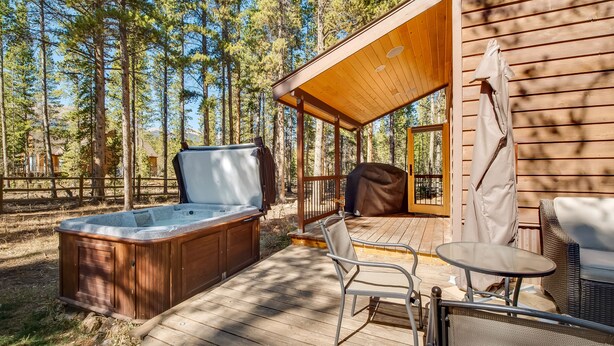 Eine Holzterrasse mit Whirlpool, Sitzgelegenheiten im Freien und einem überdachten Bereich.