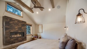 Ein Schlafzimmer mit einem großen Bett, einem Kamin, Holzbalken und einem Oberlicht.