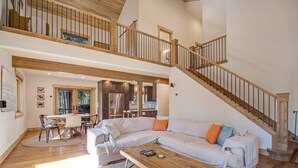 Ein geräumiger Wohnbereich mit einer großen Eckcouch, einem Holztisch und einer Treppe, die zu einer oberen Ebene führt.