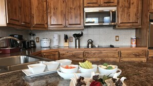 A kitchen with wooden cabinets, a stainless steel sink, and various appliances including a microwave and a coffee maker. - Peak View Retreats Family-friendly,  Rocky Mountain National Park Reg. 3230 (Estes Park)
