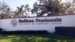 Un panneau indiquant l’entrée de la péninsule de Balboa et de la ville de Newport Beach, avec un logo et du texte.