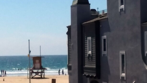 Une vue sur la plage avec une tour de surveillance et un bâtiment doté d’un balcon.