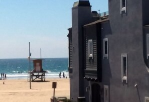 Vista a la playa con una torre de salvavidas y un edificio con balcón.