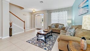 A spacious living room with a wooden coffee table, a beige sofa, and a patterned rug.