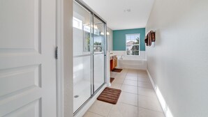 A modern bathroom with a glass shower enclosure, a bathtub, and a sink.