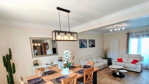 Een moderne woonkamer met een eetgedeelte, met een houten tafel, stoelen, een bank en een salontafel.