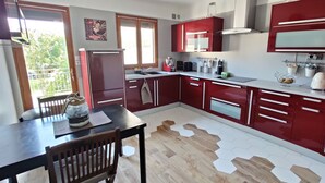 Een moderne keuken met rode kasten, een houten eettafel en een groot raam.