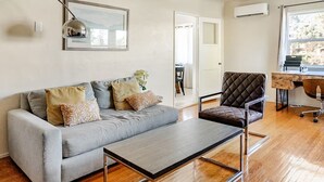 Ein modernes Wohnzimmer mit einem grauen Sofa, einem Holztisch und einem Ledersessel.