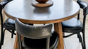 Ein runder Tisch mit einer Holzkugel auf einer gewebten Tischunterlage, umgeben von schwarzen Ledersesseln.