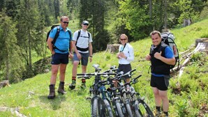 Un grupo de personas de pie en una ladera cubierta de hierba, con bicicletas estacionadas frente a ellas.