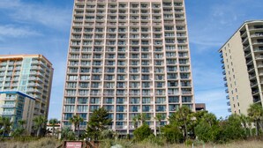 Un hotel moderno de gran altura con varios pisos, balcones y una vista despejada del entorno.