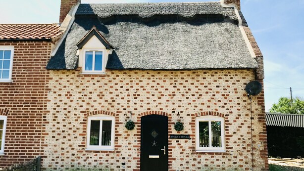 Ein Backsteinhaus mit einer schwarzen Tür, zwei Fenstern und einem Schild, auf dem "ROCKET HOUSE" steht.