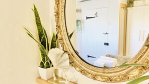 Ein Badezimmer mit einem großen, verzierten Spiegel, einer Topfpflanze und einer Meerstern-Dekoration auf einem Holzboden.